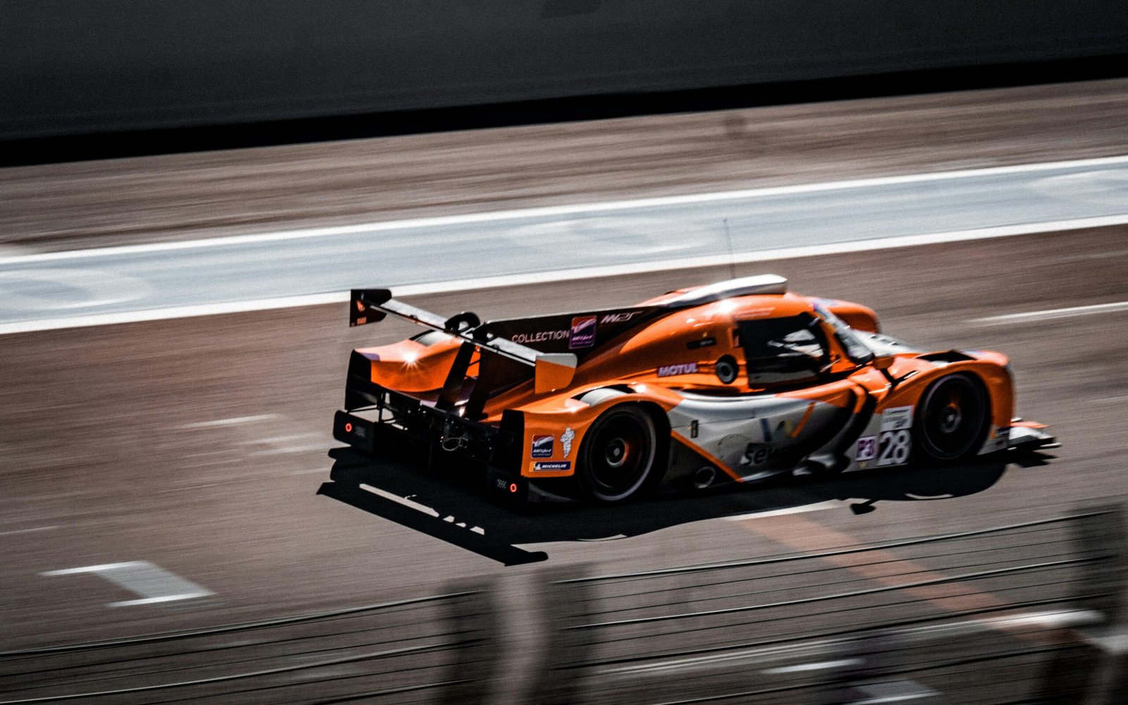 an orange race car driving down a race track